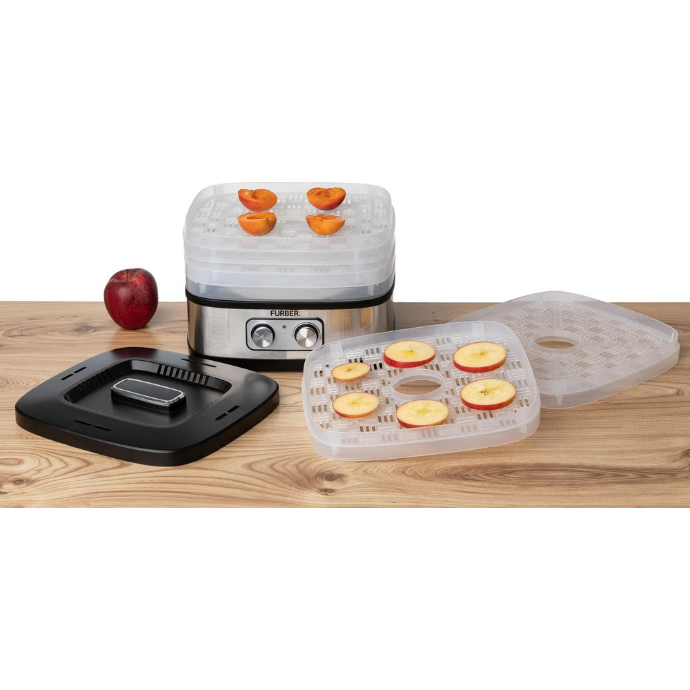 Un déshydrateur alimentaire avec des fruits sur les plateaux et une pomme à proximité.