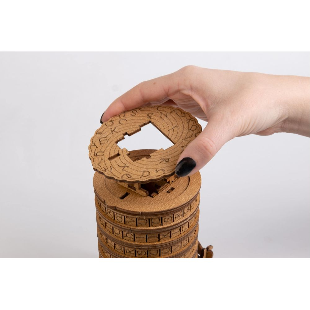 Una mano tiene una ruota di legno con lettere sopra un cilindro di legno.