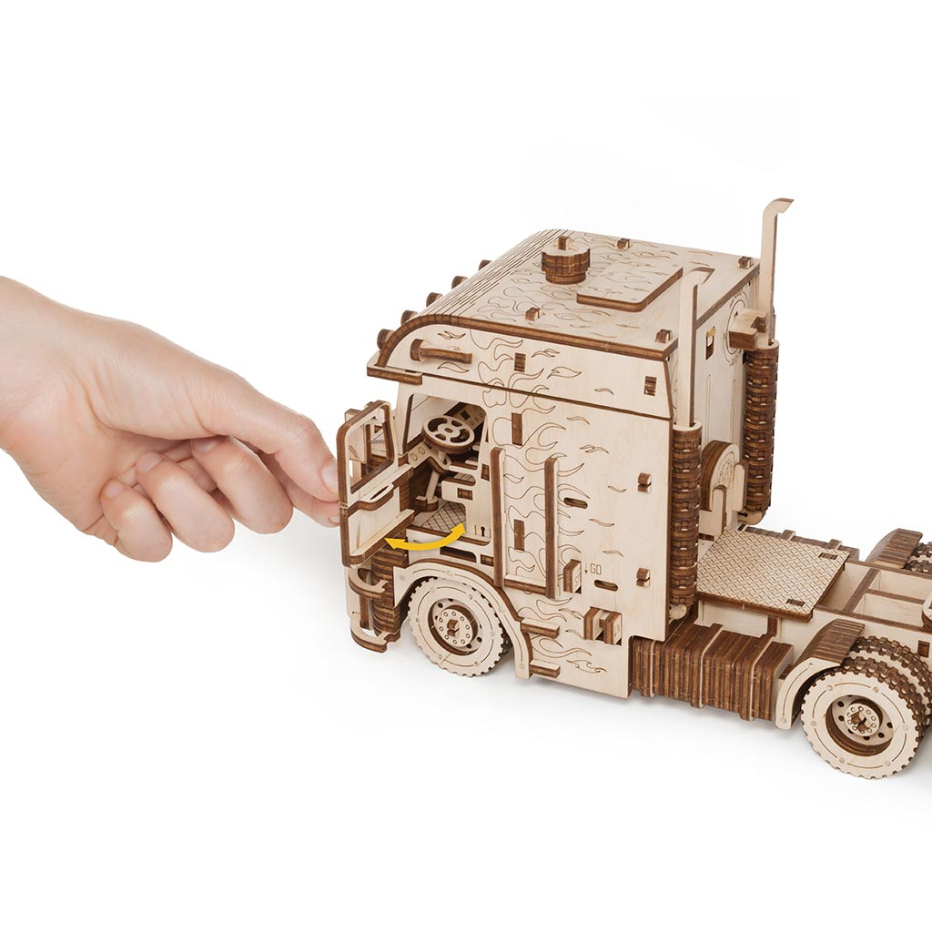 Holzmodell eines Trucks mit geöffneter Tür, eine Hand greift hinein.