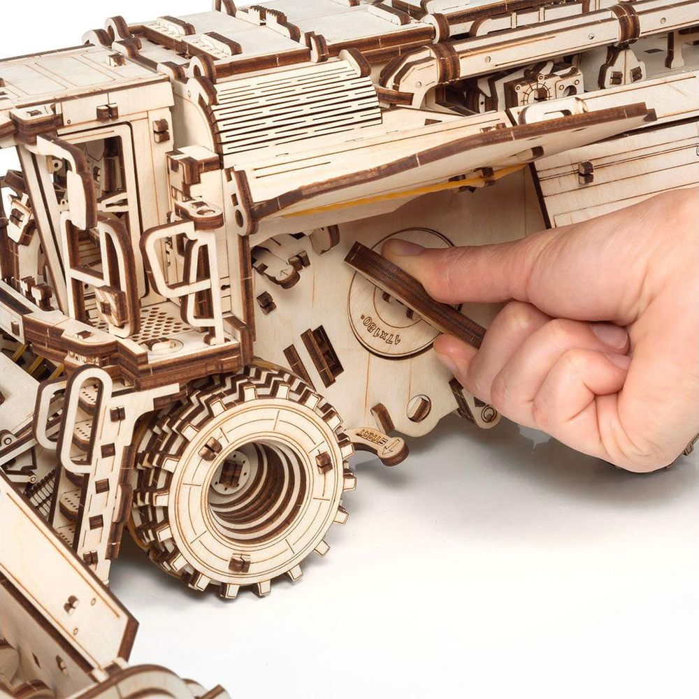 Eine Hand setzt ein Holzteil in ein Holzmodell eines Lastwagens ein.