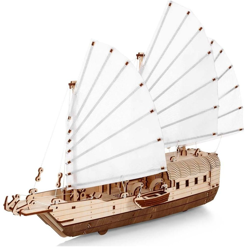 Ein Holzmodell eines Segelschiffs mit weißen Segeln und einem kleinen Beiboot.