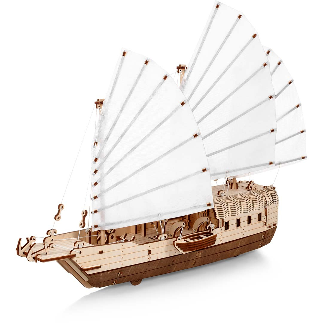 Ein hölzernes Modellschiff mit weißen Segeln und dunklem Rumpf.