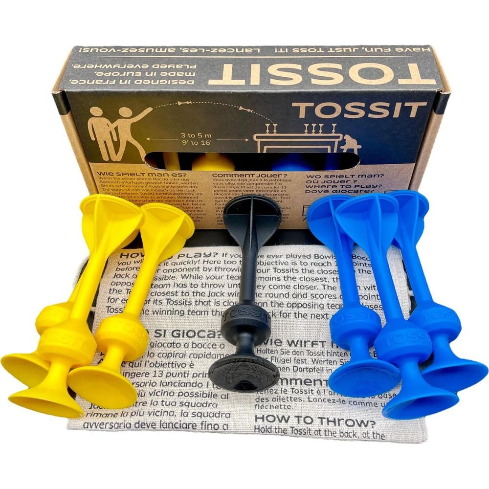 Gelbe, blaue und schwarze Tossit-Spielteile liegen vor einer Spielbox.