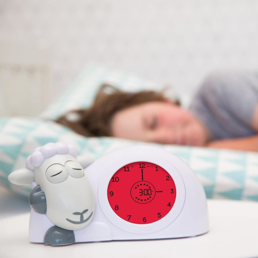 Ein Schaf-Wecker zeigt 3:00 Uhr, während eine Person im Bett schläft.