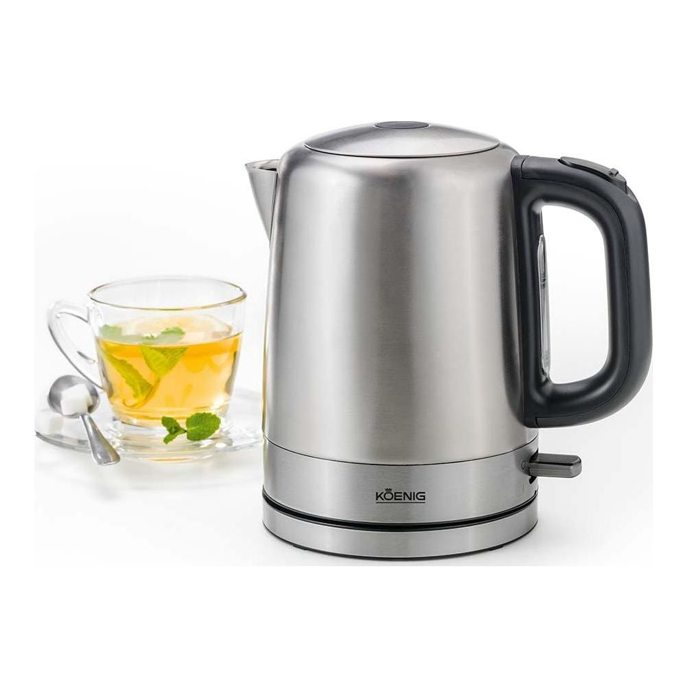 Ein silberner Wasserkocher mit schwarzem Griff neben einer Teetasse mit Zitrone und Minze.