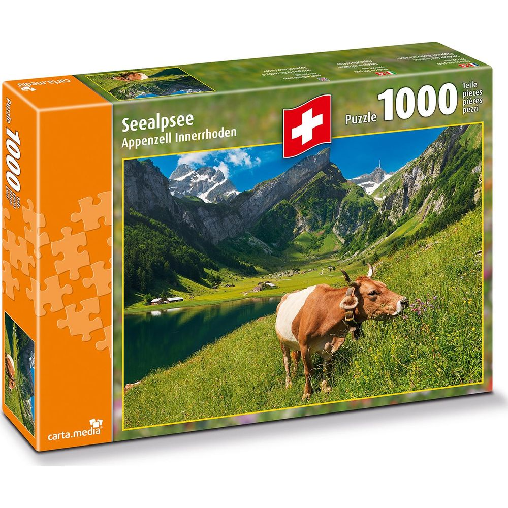 Una mucca su un prato verde davanti a un lago di montagna e cime.