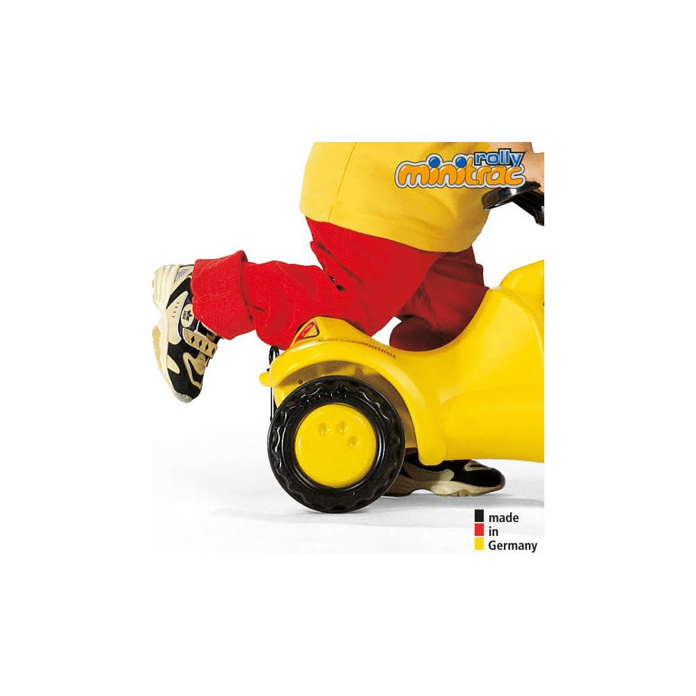 Ein Kind in roter Hose und gelbem Oberteil fährt ein gelbes Spielzeugauto.