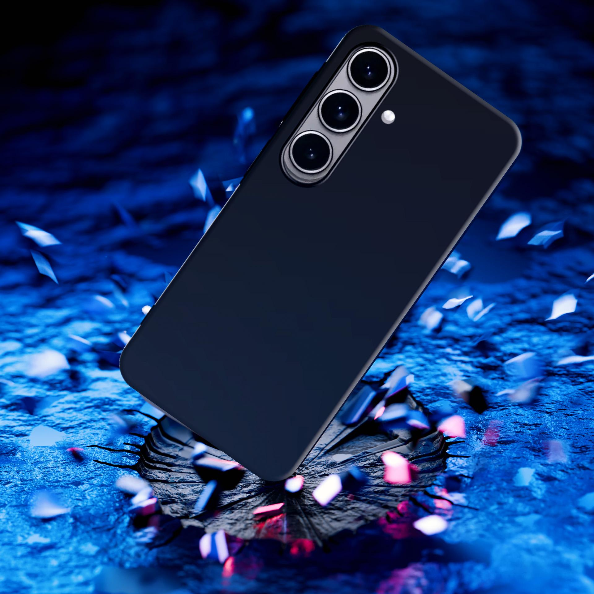 Czarny smartfon z trzema aparatami spada na niebieską, potłuczoną powierzchnię.