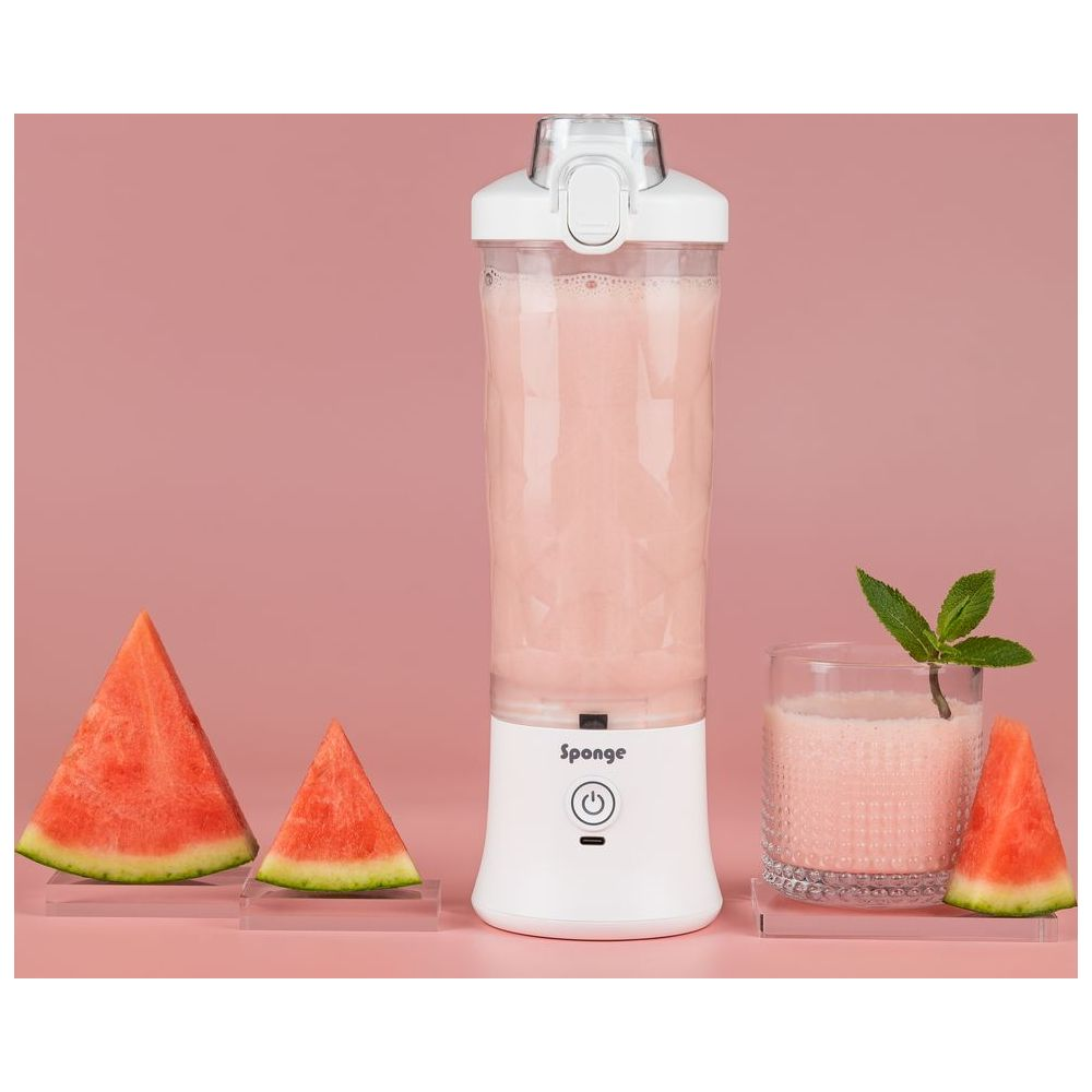 Un frullatore bianco con succo rosa, accanto a fette di anguria e un bicchiere di succo.