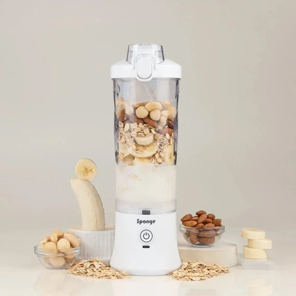 Un frullatore portatile bianco riempito con ingredienti come noci, avena e banana.