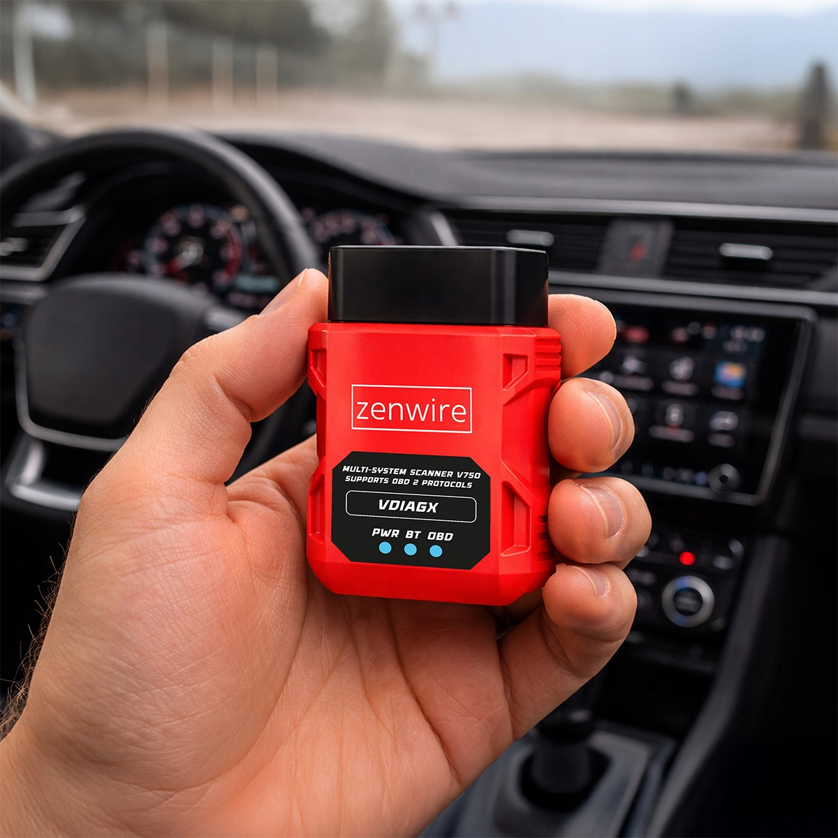 Czerwone narzędzie diagnostyczne OBD-II trzymane w samochodzie.