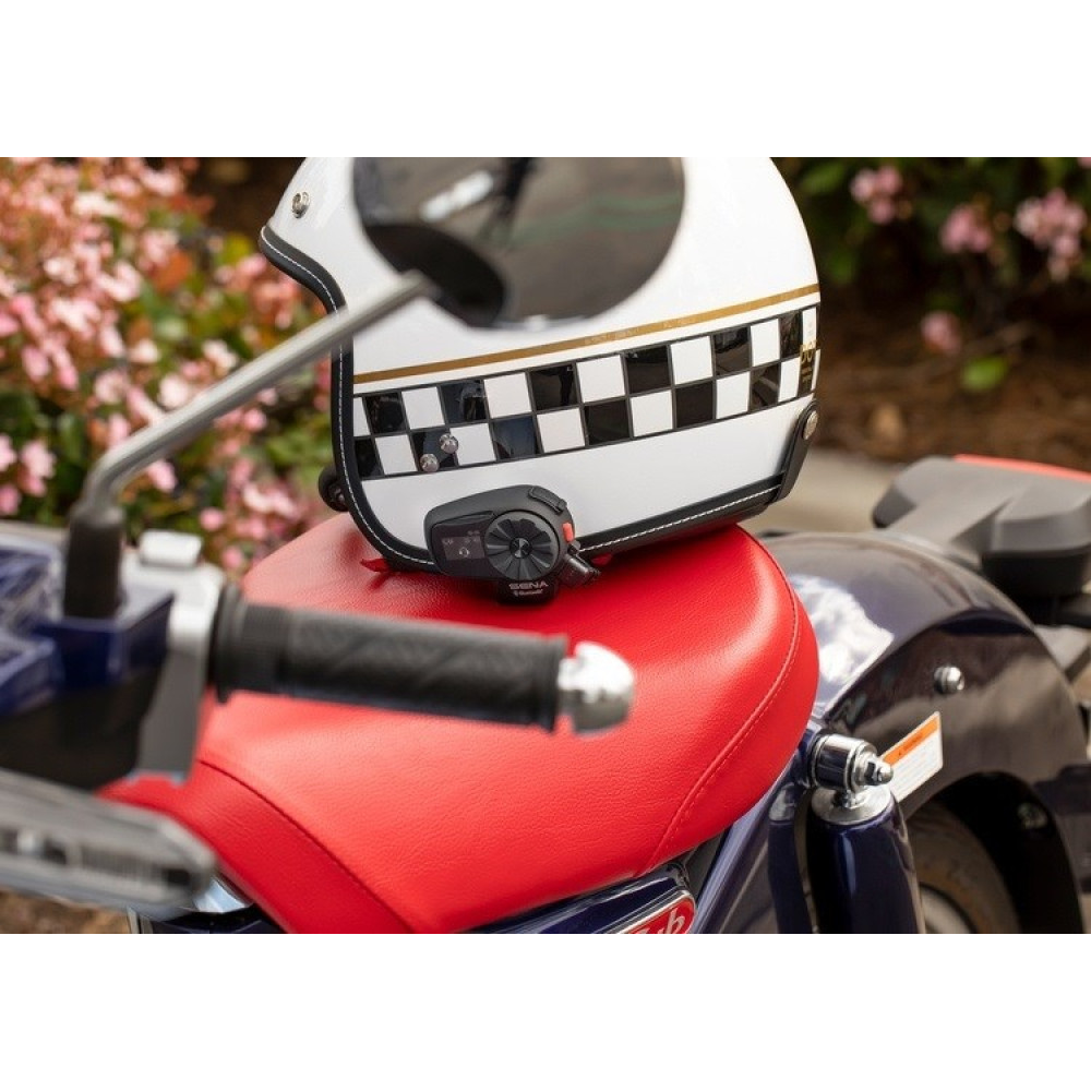 Biały kask z wzorem szachownicy spoczywa na siedzeniu motocykla.