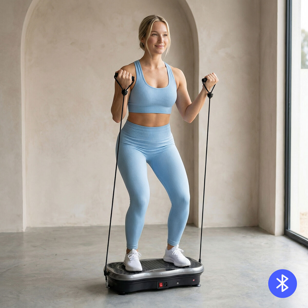 Eine Frau in blauem Sport-BH und Leggings trainiert mit Widerstandsbändern auf einer Vibrationsplatte.
