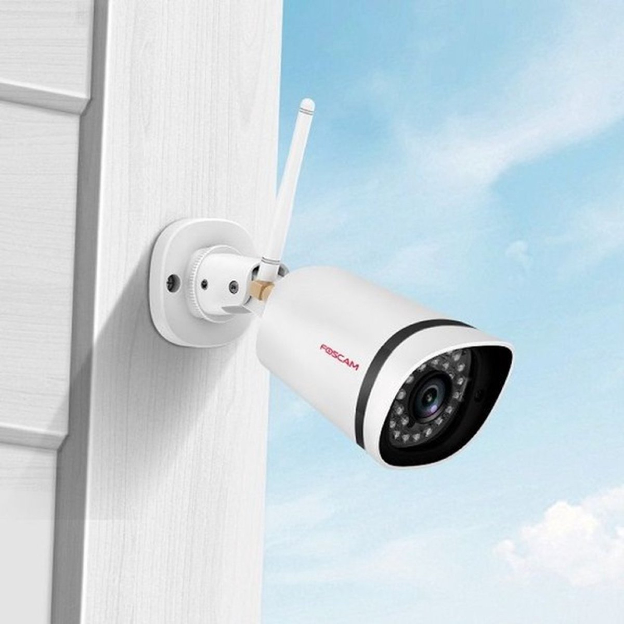 Een witte beveiligingscamera met antenne is aan een witte muur bevestigd.