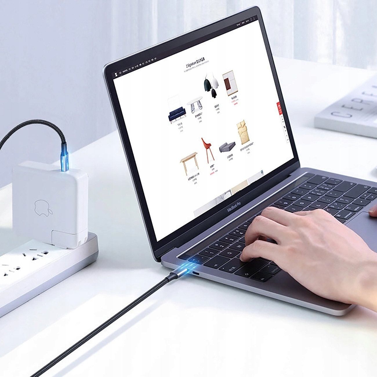 Laptop podłączony do białej listwy zasilającej. Kabel prowadzi do laptopa.