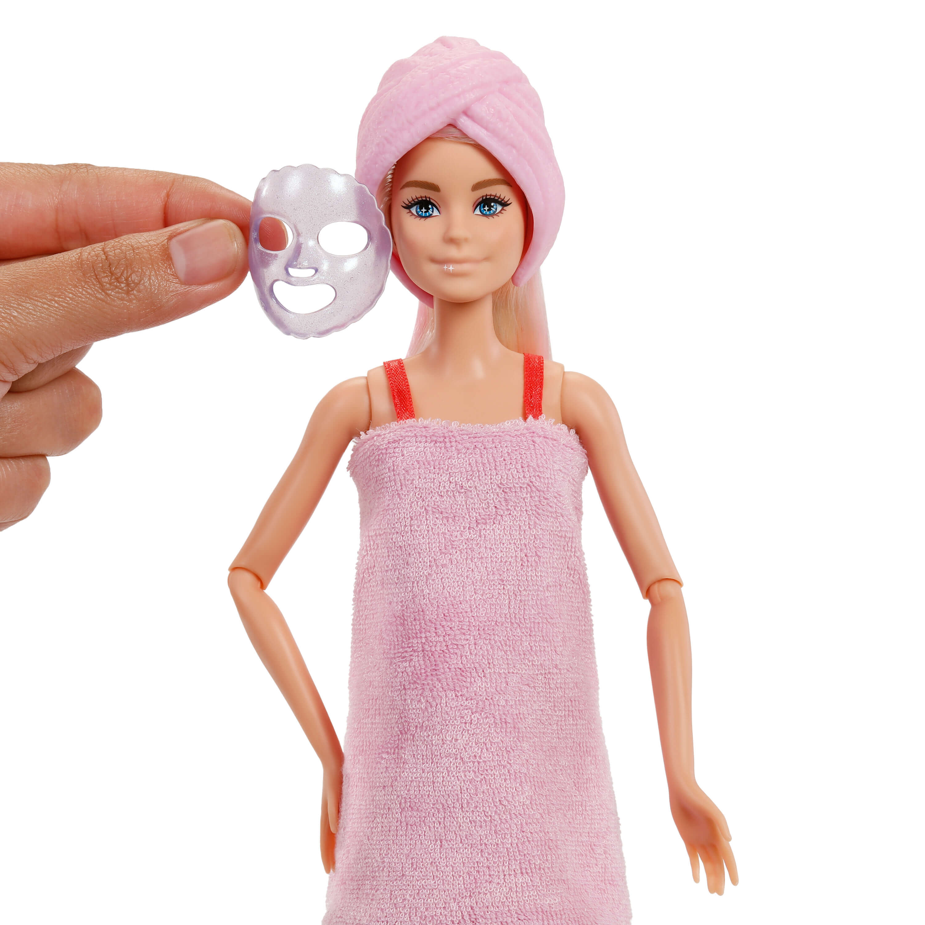 Barbie mit rosa Handtuch und Gesichtsmaske in der Hand vor weißem Hintergrund.