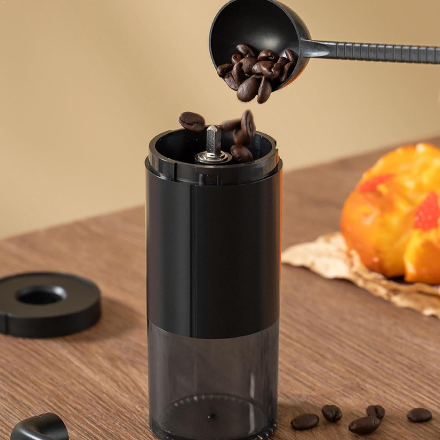 Kaffeebohnen werden aus einem Löffel in eine Kaffeemühle gegeben.