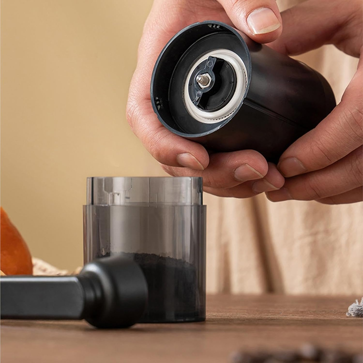 Hände halten einen schwarzen elektrischen Kaffeemühle mit Mahlgut.