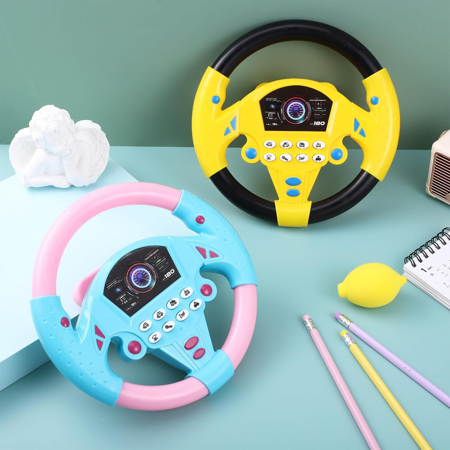 Zwei Spielzeug-Lenkräder, eins gelb, eins blau/pink, mit Zubehör.