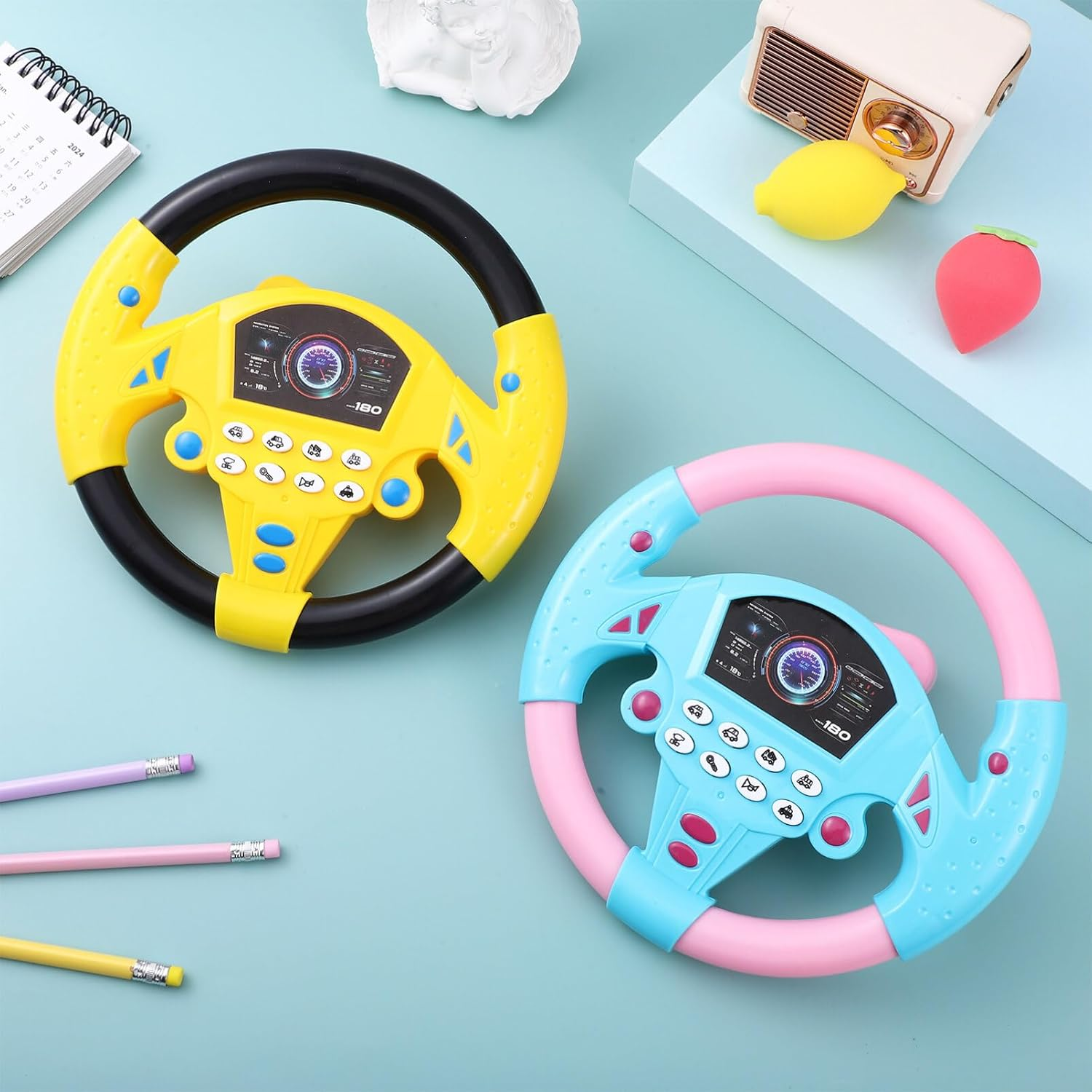 Zwei bunte Spielzeug-Lenkräder, eins gelb, eins blau, mit Knöpfen und Display.