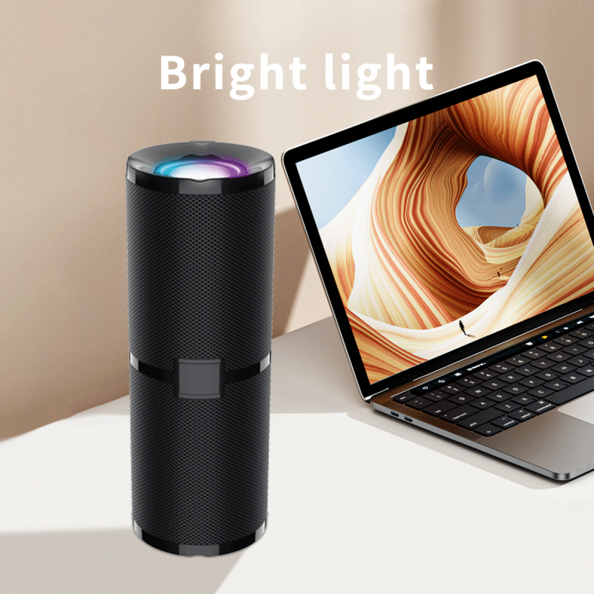 Schwarzer Lautsprecher mit farbigen Lichtern neben einem Laptop mit abstraktem Hintergrund.