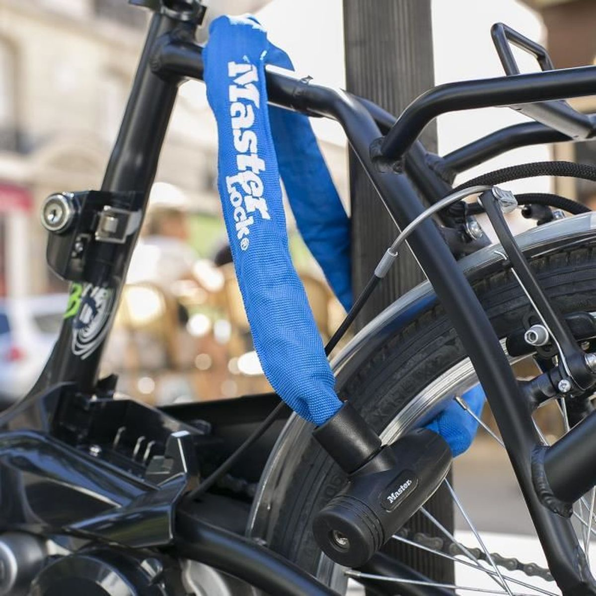 Bicicletta nera assicurata con un lucchetto a catena Master Lock blu a un palo.