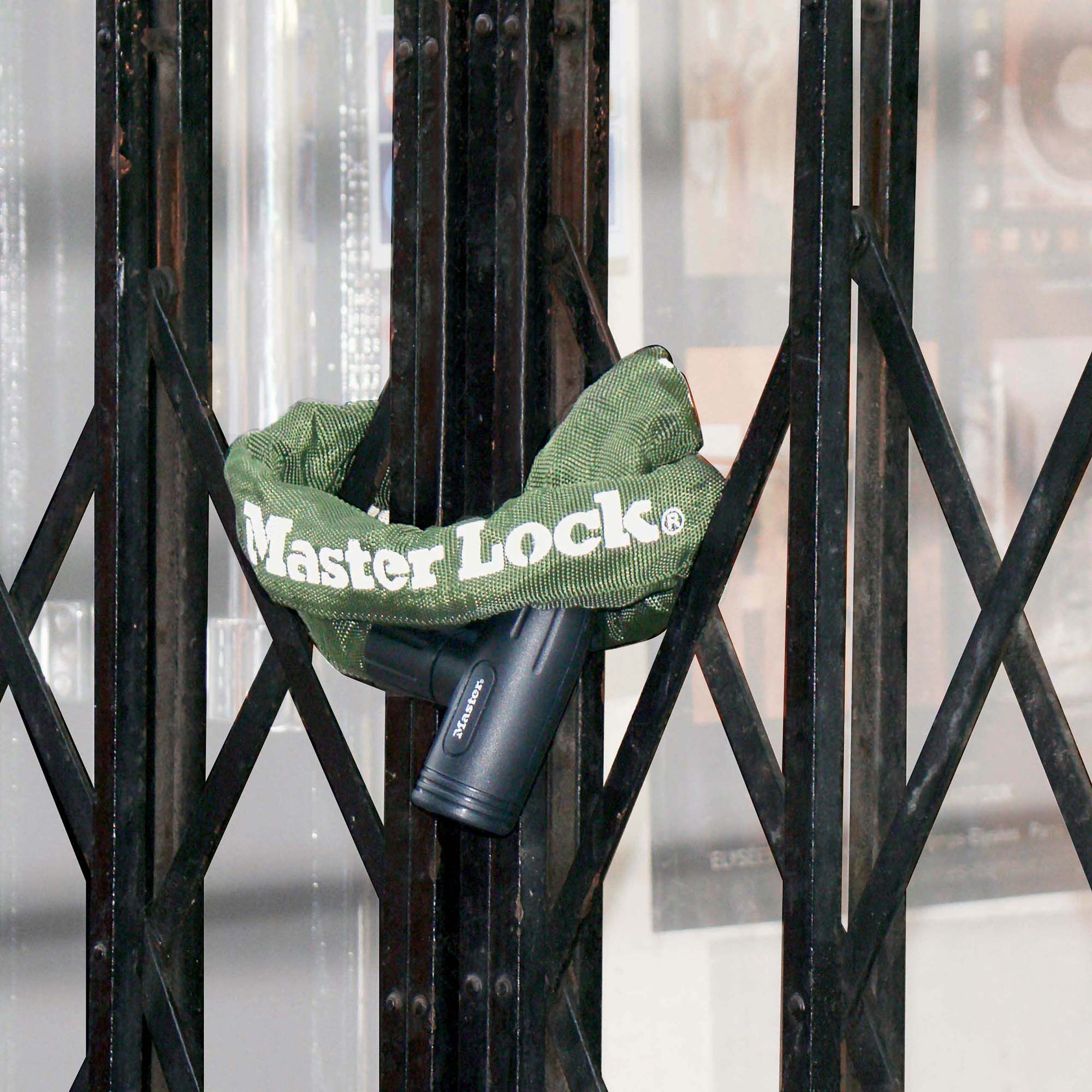 Un lucchetto a catena Master Lock verde fissato a un cancello a soffietto nero.
