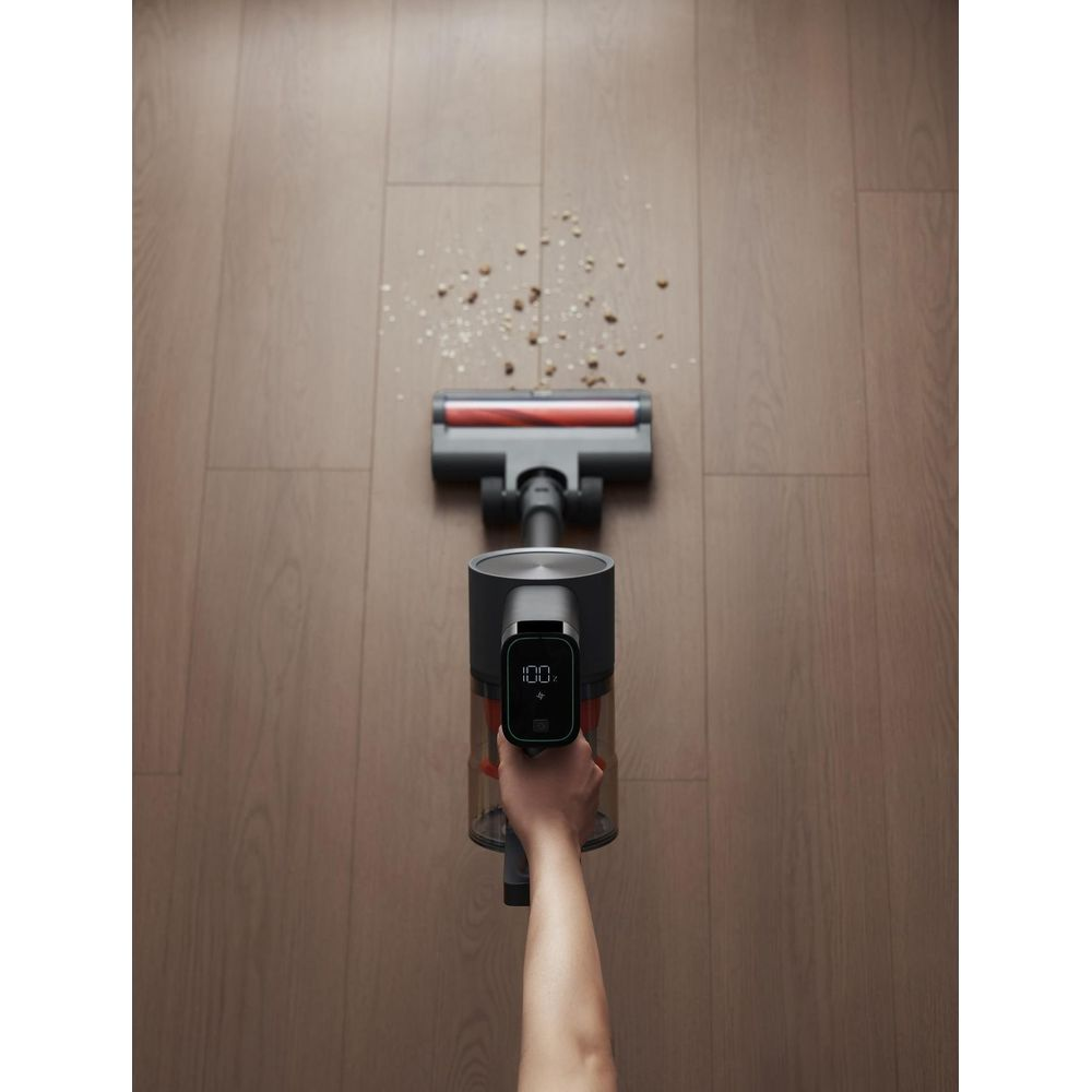 Ręczny odkurzacz czyści brud z drewnianej podłogi.