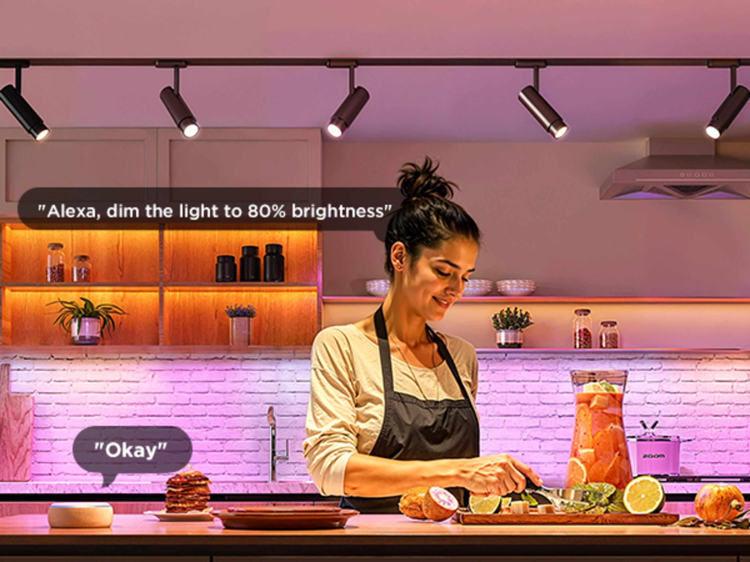 Donna in cucina prepara cibo, illuminata da luce rosa.