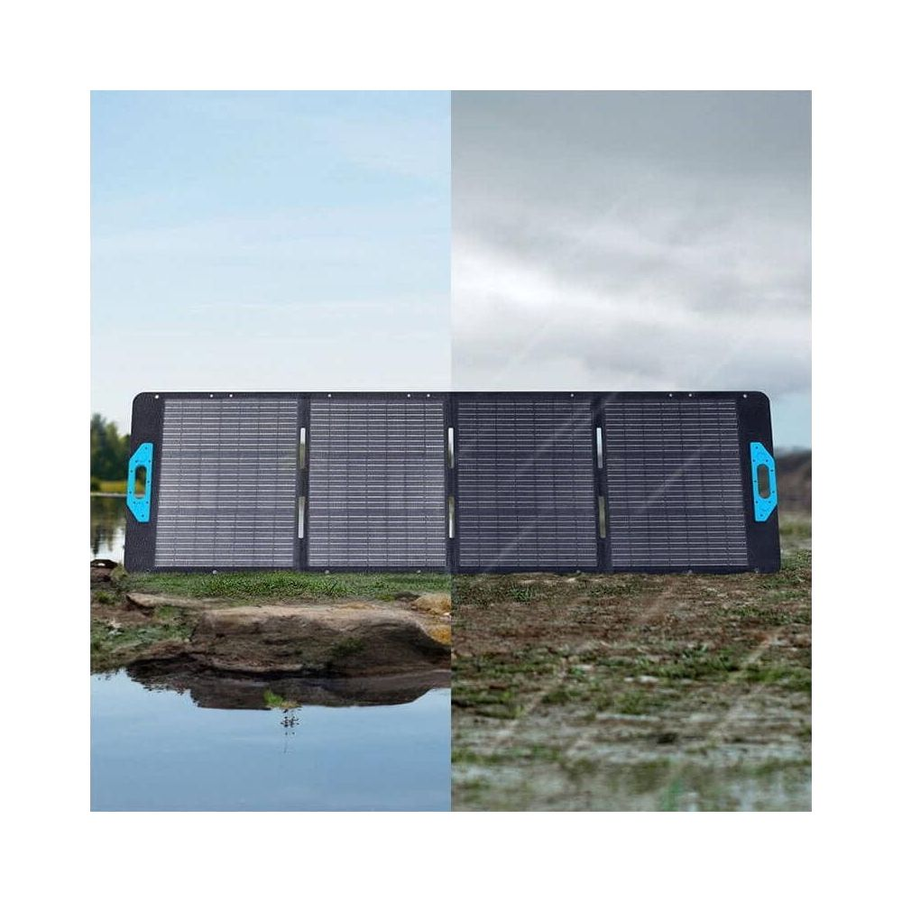 Składany panel słoneczny leży na trawie. W tle woda i niebo.