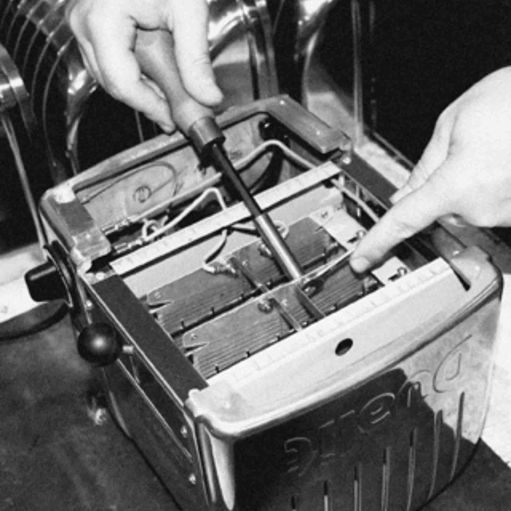 Zwei Hände reparieren einen Toaster, eine mit einem Schraubendreher.