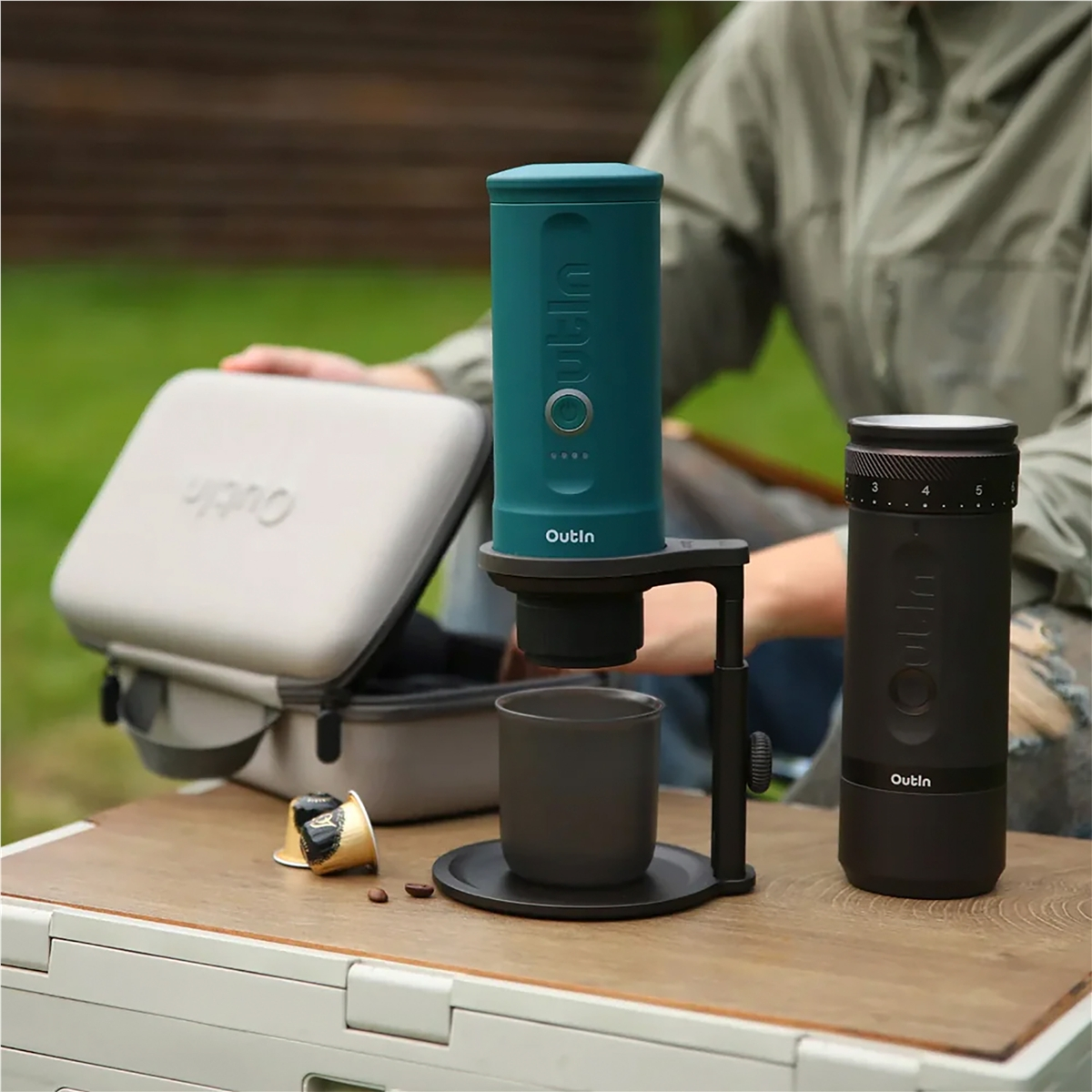 Una cafetera turquesa se sitúa sobre una taza en una mesa.