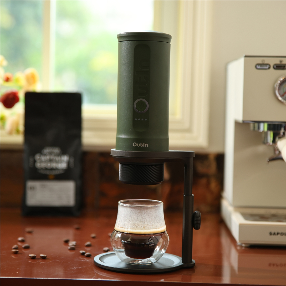 Cafetera verde sobre vaso de café. Granos de café esparcidos alrededor.