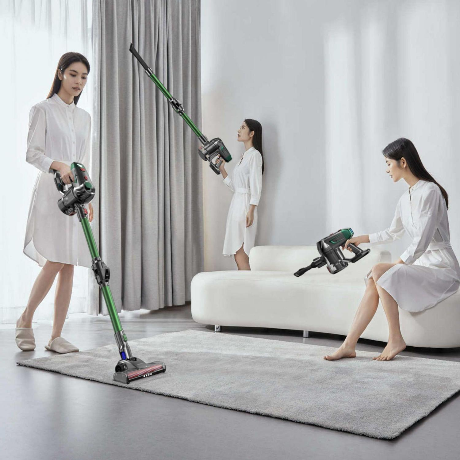 Drei Frauen in weißen Kleidern benutzen einen grünen Staubsauger in einem modernen Wohnzimmer.