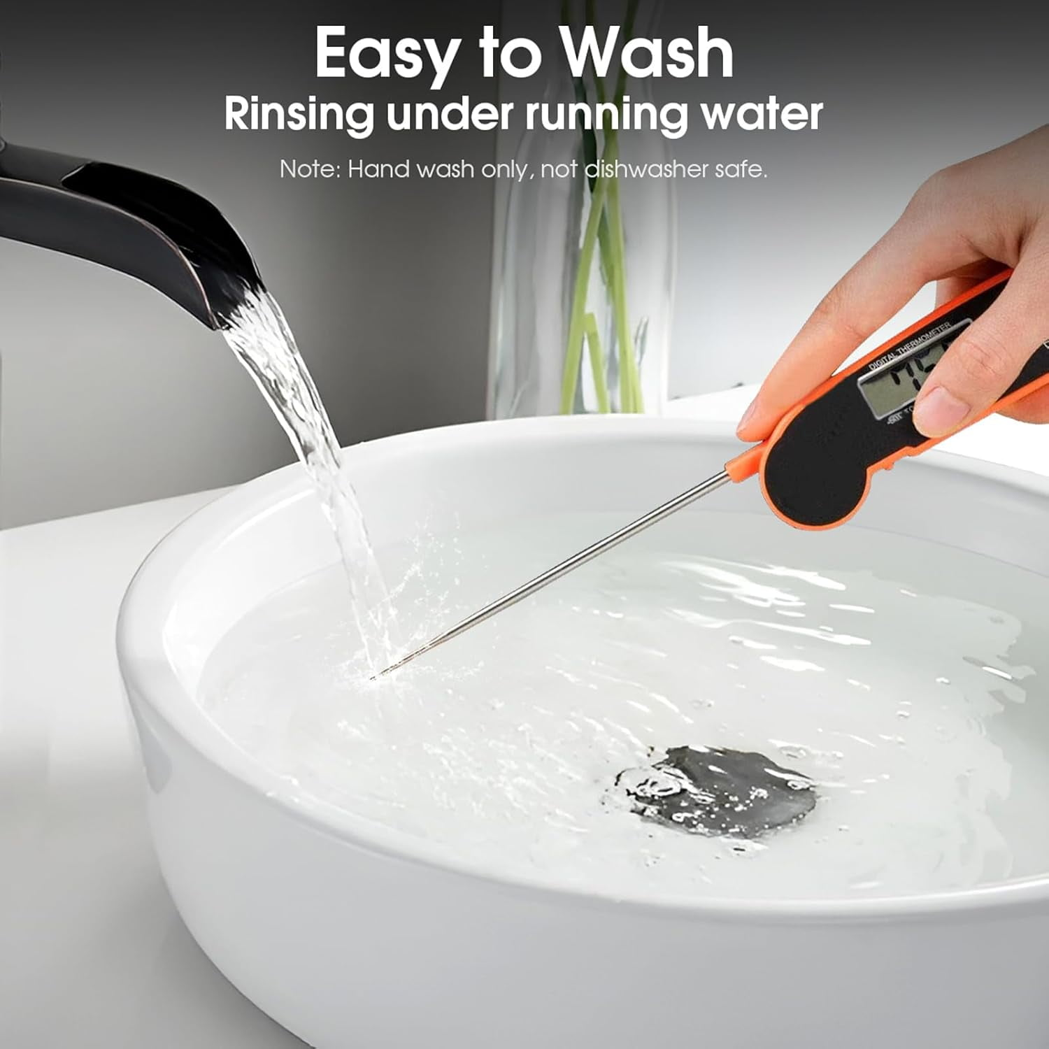Ein oranges Digitalthermometer wird in einem weißen Waschbecken unter fließendem Wasser gehalten.