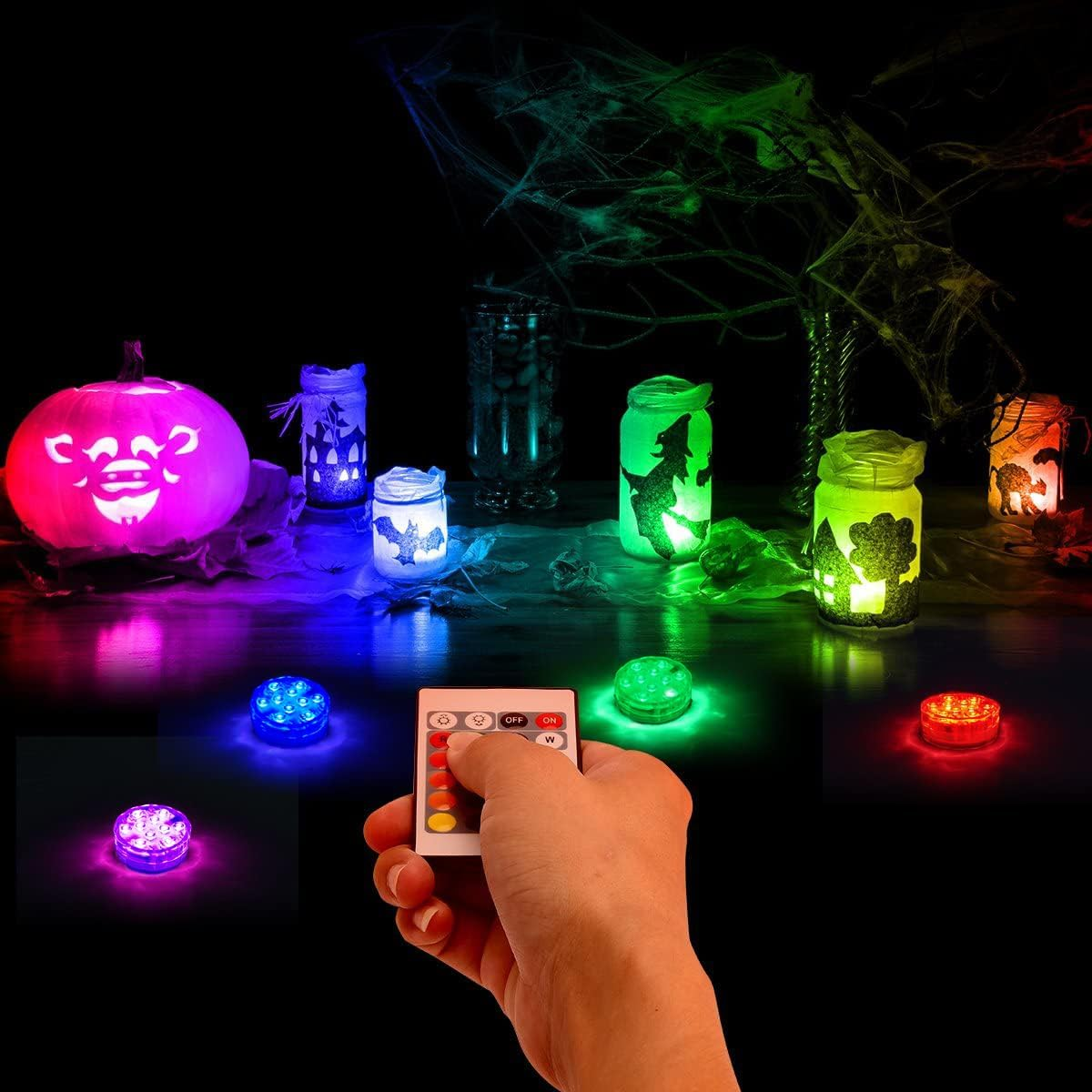 Halloween-Dekoration: leuchtender Kürbis, Gläser mit gruseligen Figuren, Spinnweben und ferngesteuerte LEDs.