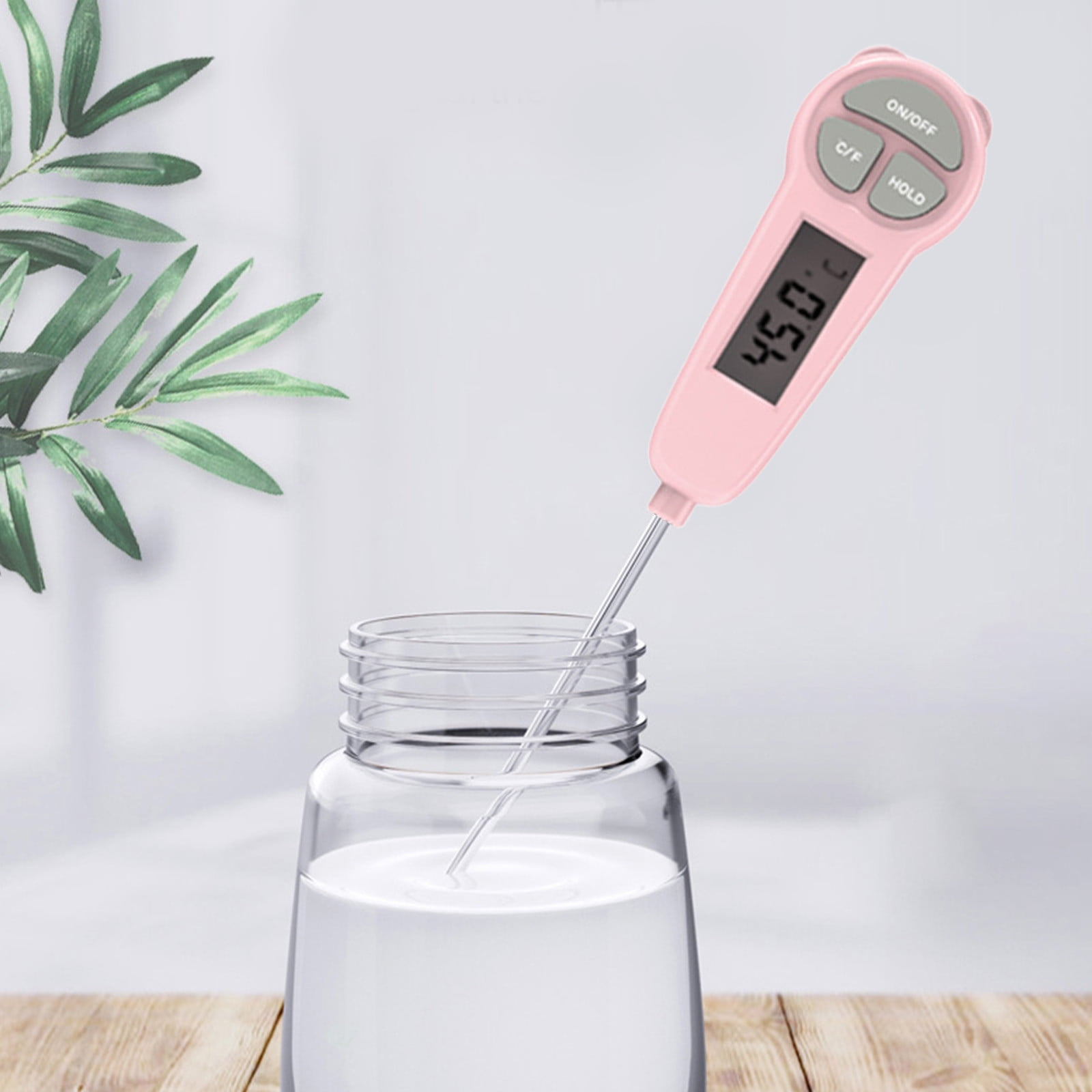 Ein rosa Thermometer misst die Temperatur einer Flüssigkeit in einem Glasbehälter.