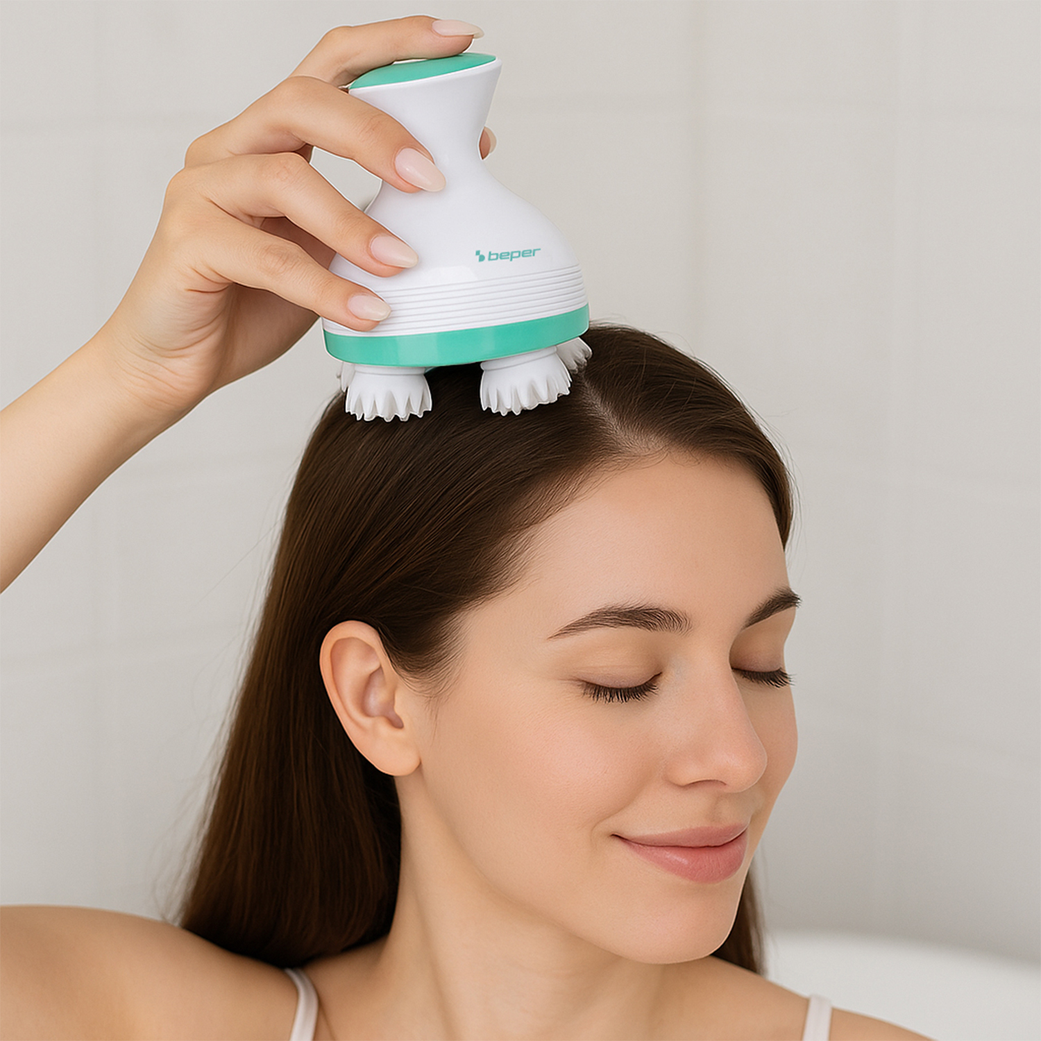 Una mano usa un massaggiatore per cuoio capelluto bianco e verde sulla testa di una donna.
