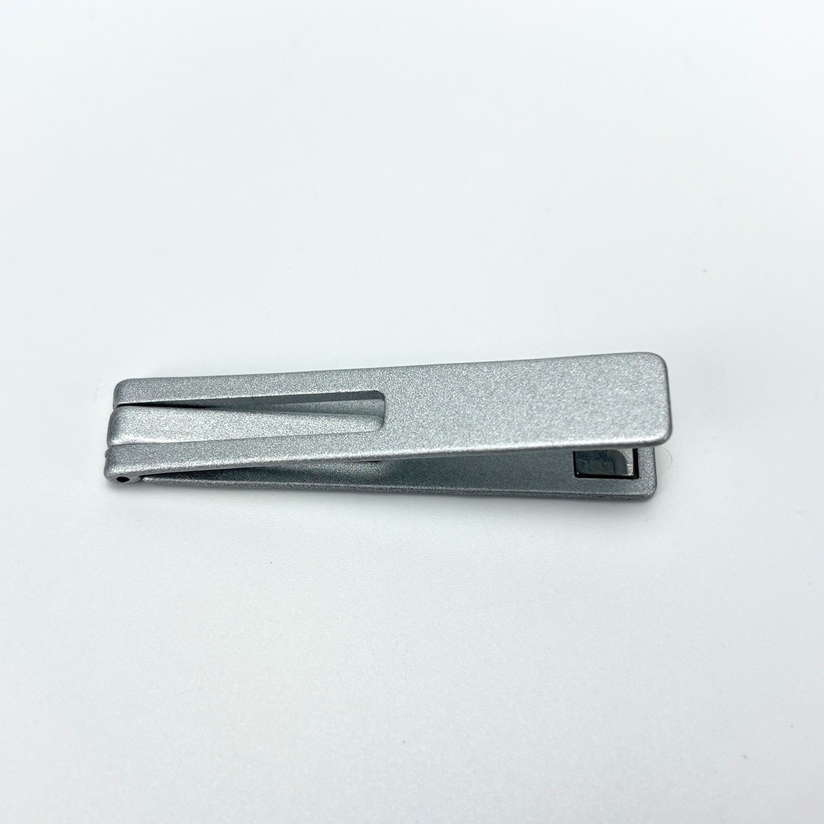 Srebrna obcinaczka do paznokci z otworem na białym tle.