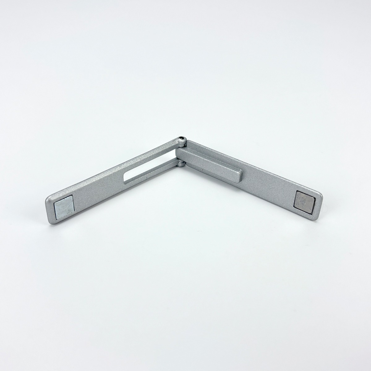 Srebrny, składany kątomierz z magnesami na końcach na białym tle.