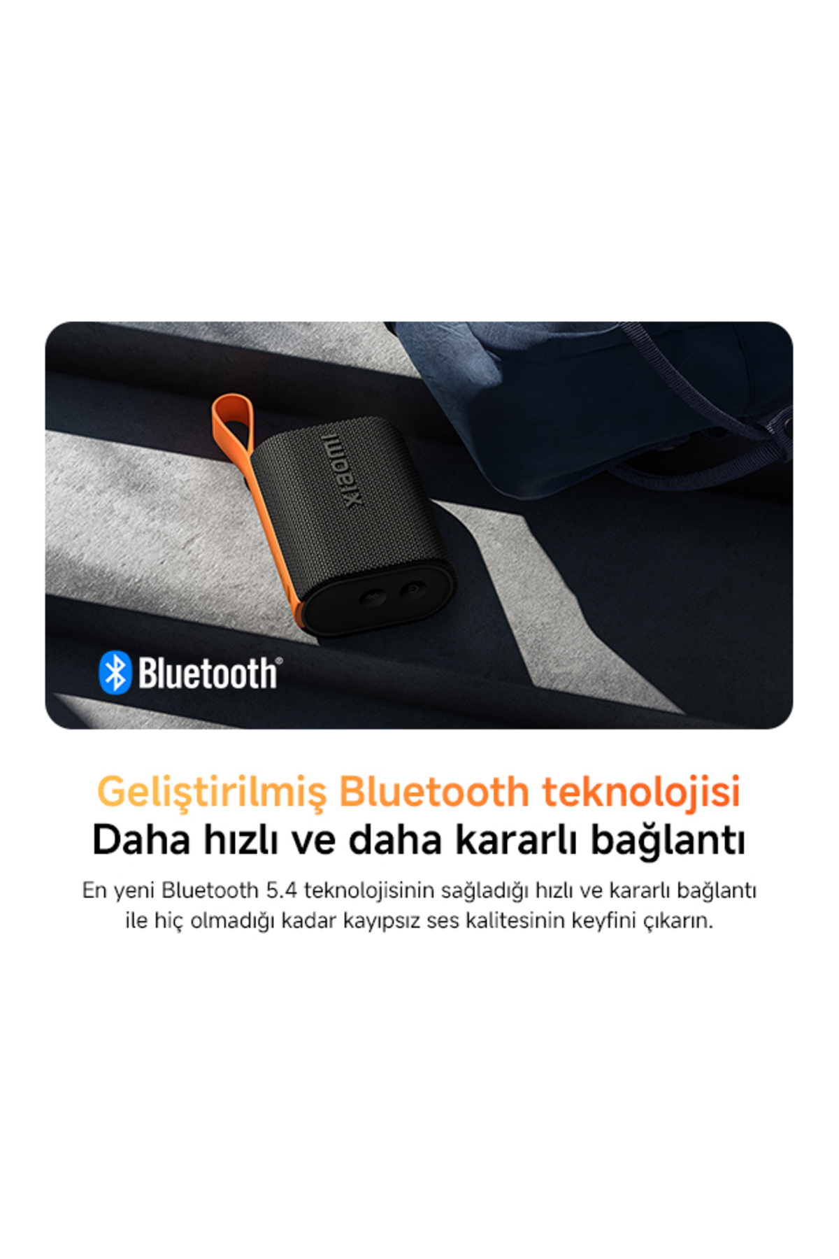 Schwarzer Xiaomi Bluetooth-Lautsprecher mit orangem Band, neben einer dunkelblauen Tasche.