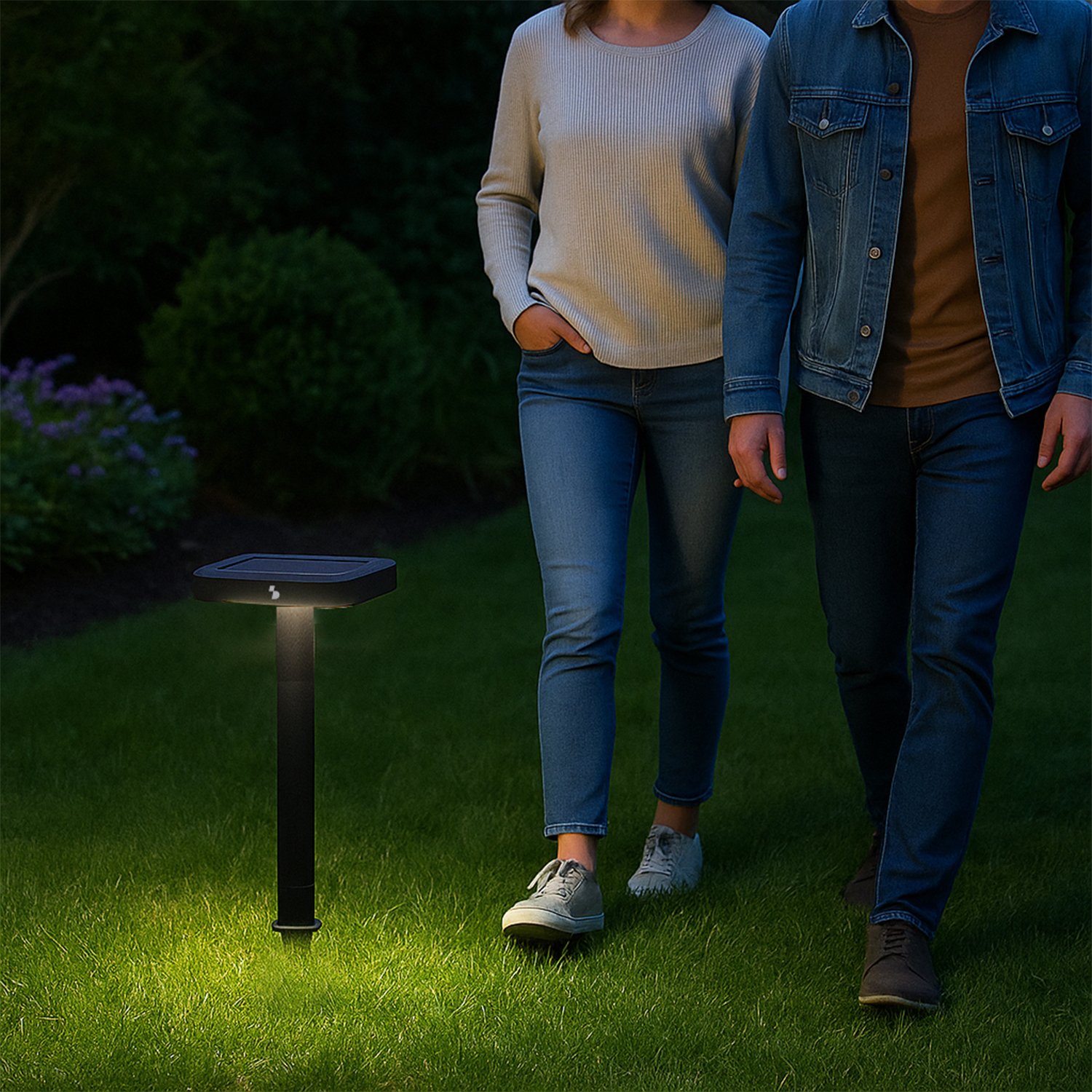 Due persone camminano sull'erba. Una lampada illumina il percorso.