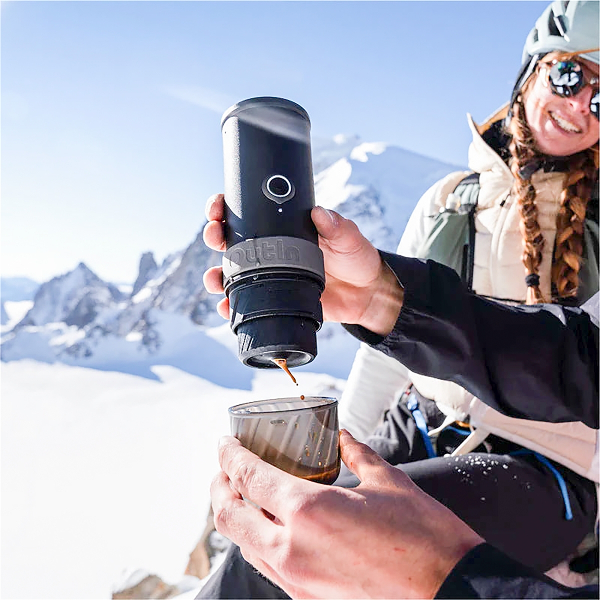 Eine Person brüht Kaffee in den Bergen mit einem tragbaren Espressomaschine.