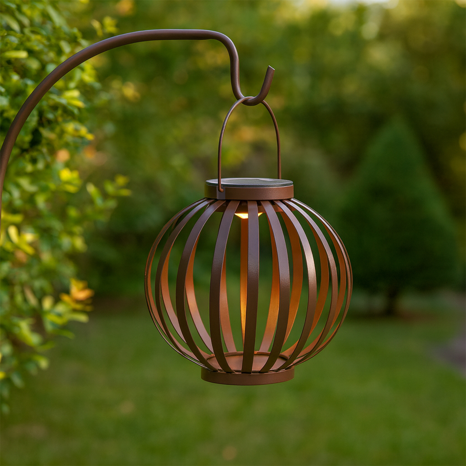 Una lanterna di bronzo con design a gabbia è appesa a un gancio in un giardino.