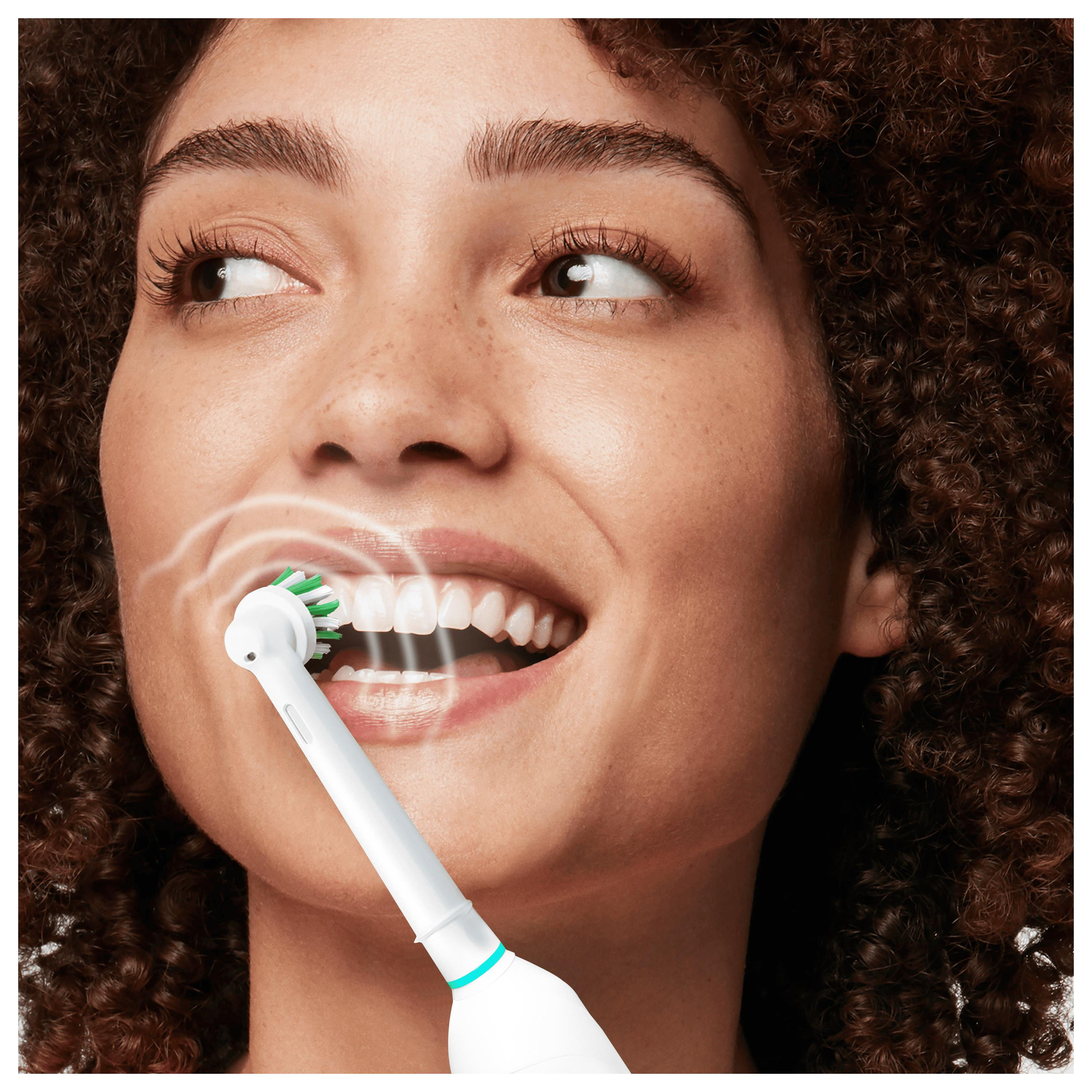 Una donna si lava i denti con uno spazzolino elettrico.