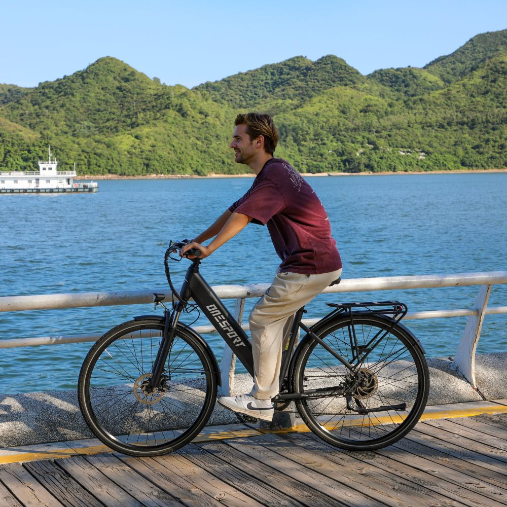 Uomo in bicicletta su un lungomare di legno vicino all'acqua.