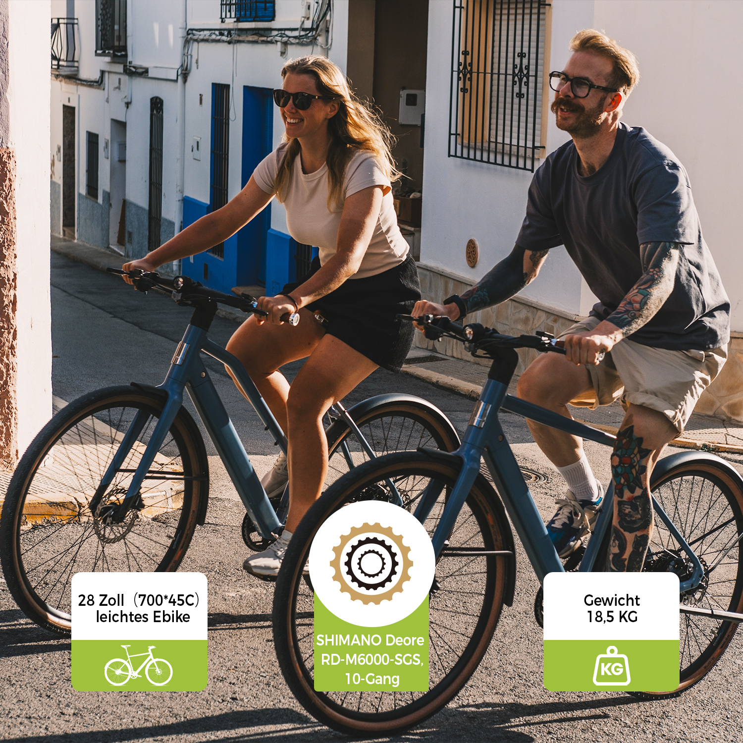 Mann und Frau fahren E-Bikes auf einer Gasse mit weißen Häusern.