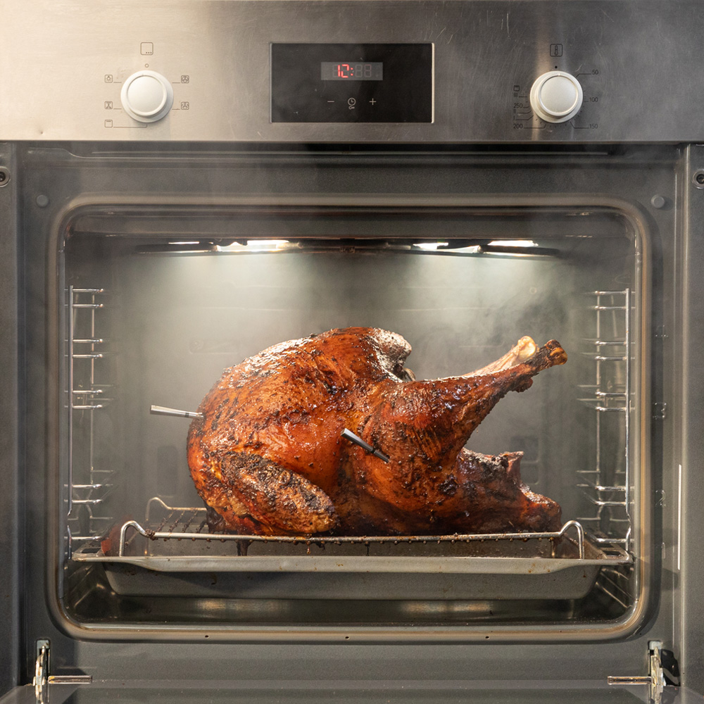 Ein gebräunter Truthahn wird im Ofen auf einem Rost gebraten, Dampf steigt auf.