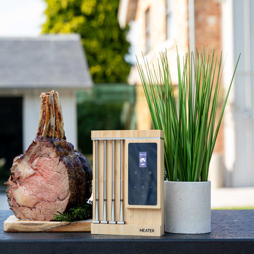Ein Braten mit Knochen und ein Fleischthermometer auf einem Tisch.