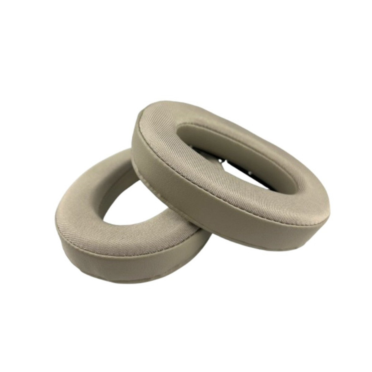 Due cuscinetti auricolari beige per cuffie giacciono uno accanto all'altro su sfondo bianco.
